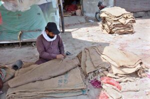 A craftsman repairs the sacks, ensuring that each one is ready for trade.