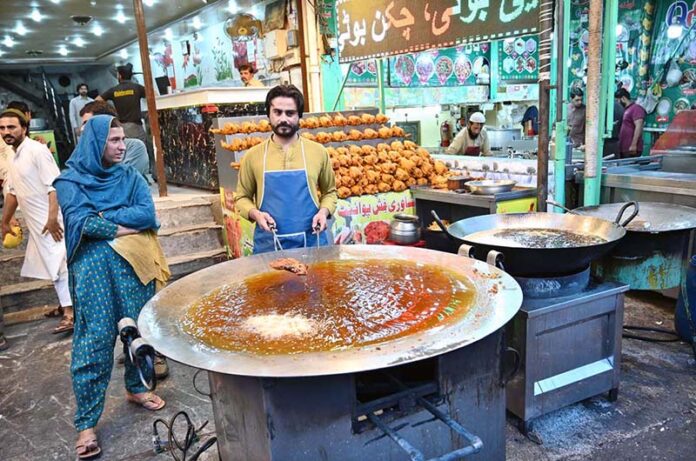 A vendor busy frying chicken to attract customers at his setup near Six Road Area in the City