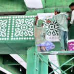 Laborers busy painting decorative designs on flyover walls using stencils, as part of ongoing development work to enhance the city’s beauty