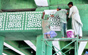 Laborers busy painting decorative designs on flyover walls using stencils, as part of ongoing development work to enhance the city’s beauty