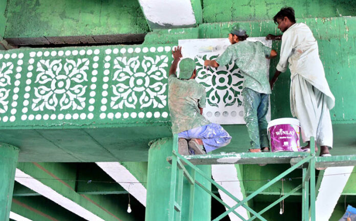 Laborers busy painting decorative designs on flyover walls using stencils, as part of ongoing development work to enhance the city’s beauty