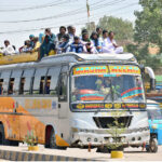 Passengers travel on the rooftop of a bus along Jail Road, in violation of traffic laws, posing a serious safety risk