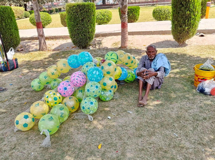 An aged man displays baloons at Chenab Park for livelihood