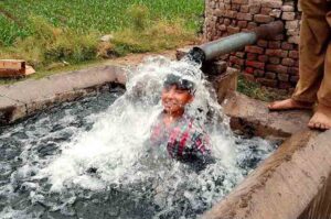 A boy cools off by bathing in a tube well during the scorching heat in Chiniot.