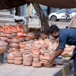 A vendor displaying beautiful clay pots at his roadside setup to capturing the attention of passersby