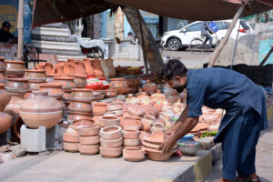 A vendor displaying beautiful clay pots at his roadside setup to capturing the attention of passersby