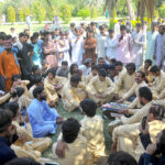 A man playing the harmonium while a large number of people enjoy the performance on the 3rd day of Eid ul Fitr celebrations at a public park