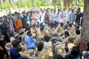 A man playing the harmonium while a large number of people enjoy the performance on the 3rd day of Eid ul Fitr celebrations at a public park