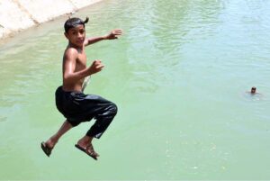 Youngsters jumping and bathing in the water canal to get some relief from hot weather in the city.
