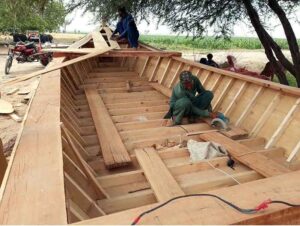 Skilled carpenters expertly crafts a new wooden boat along the banks of River Chenab in Chiniot.