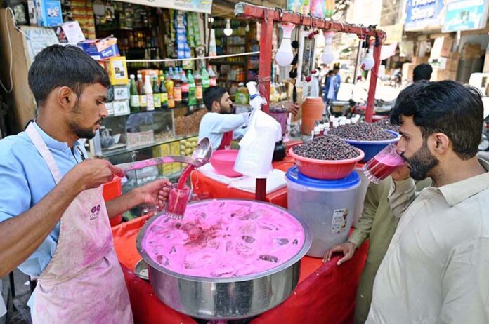A street vendor sells chilled falsa drinks to quench the thirst of passersby under the blazing sun at Pakistan Chowk