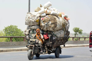 A tri-cycle rickshaw holder transports scrap in site area to earn a livelihood for his family.