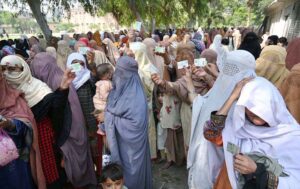 Women show their ID cards while waiting for their turn at a BISP cash distribution point at Government No.1 School, GT Road in provincial capital