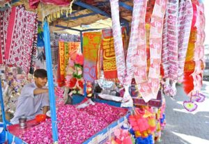 A vendor displays fresh rose petals and garlands to attract passersby near Bakrani Tower Chowk.