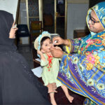 A lady health worker administers polio drops to a child during the ongoing anti-polio campaign