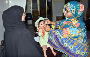 A lady health worker administers polio drops to a child during the ongoing anti-polio campaign