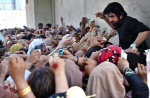 Women show their ID cards while waiting for their turn at a BISP cash distribution point at Government No.1 School, GT Road in provincial capital