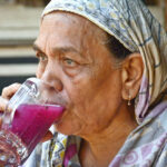 An elderly woman drinks a sweet beverage at Kharadar area to get relief from the scorching heat in the Provincial Capital