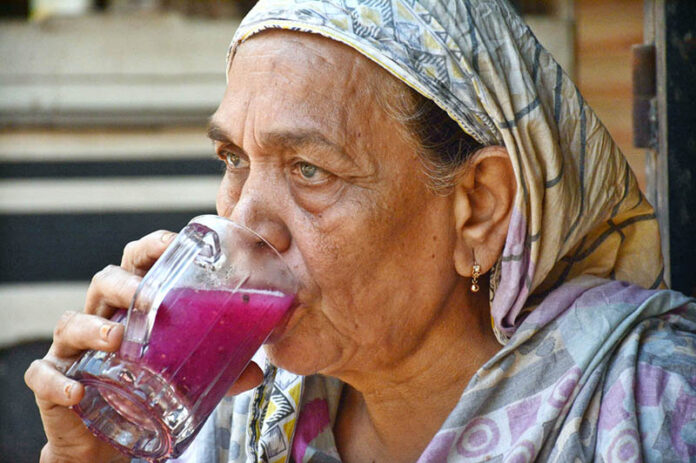 An elderly woman drinks a sweet beverage at Kharadar area to get relief from the scorching heat in the Provincial Capital