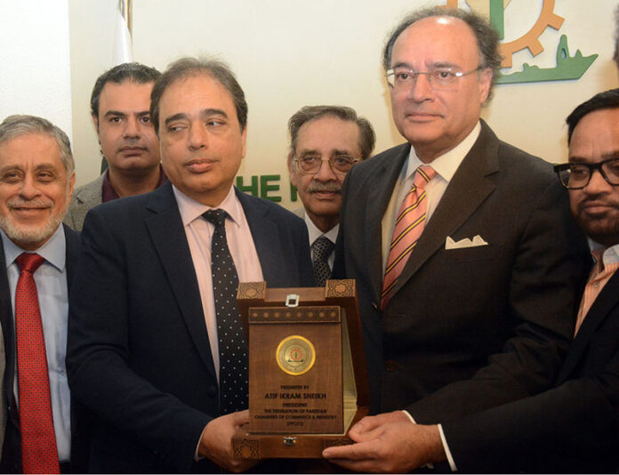 The Federal Finance Minister, Muhammad Aurangzeb receiving a souvenir shield from SVP Federation of Pakistan Chambers of Commerce and Industry Saqib Fayaz Magoon during a visit of FPCCI Head office