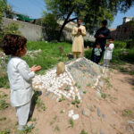 A family offering Fateha on the graves of their deceased family members in graveyard on the occasion of Eidul Fitr