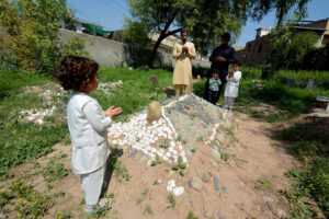 A family offering Fateha on the graves of their deceased family members in graveyard on the occasion of Eidul Fitr
