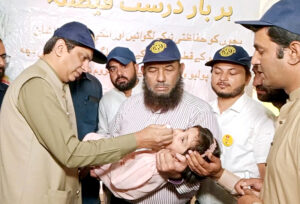 Commissioner Amir Kareem Khan is administering polio drops to a child during the inauguration of the 3-day Anti-Polio Campaign.
