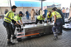 Staff at the airport are placing the body of a Pakistani who died in the Libya boat tragedy at the cargo terminal
