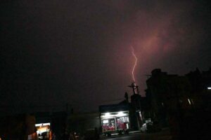 Lightning flashes and strikes the ground amid stormy weather at night.