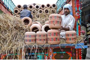 Workers are busy unloading clay made water coolers from a delivery truck near Zulfiqar Bagh.