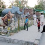 People are capturing memorable moments by taking pictures of children with various animal statues outside the zoo