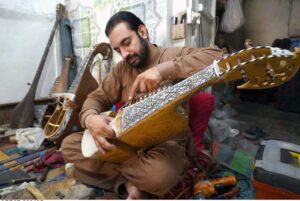 A man busy in repairing traditional musical instrument rabab at his workplace.