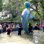 Children enjoy the artificial dolphin water slide at the zoo on the third Eid-ul-Fitr celebrations in the city