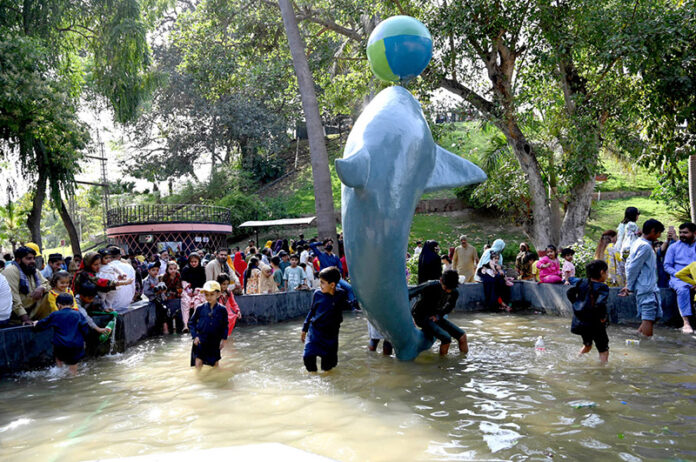 Children enjoy the artificial dolphin water slide at the zoo on the third Eid-ul-Fitr celebrations in the city