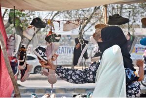 Woman purchasing used shoes from a street vendor at Korangi area