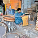 A sieve maker crafts iron sieves and traditional bamboo stick sieves to sell at his workplace in the provincial capital