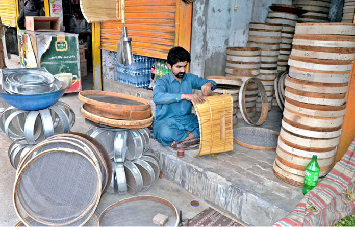 A sieve maker crafts iron sieves and traditional bamboo stick sieves to sell at his workplace in the provincial capital