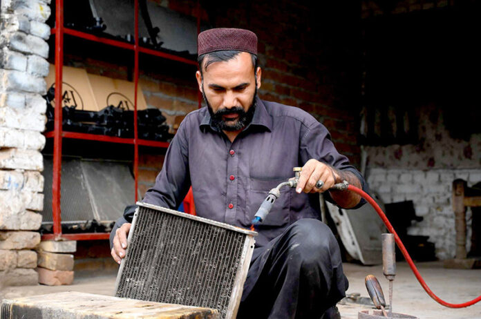 An autos mechanic repairs vehicles' radiators at New Shoba Market, keeping engines summer-ready