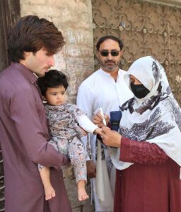 Polio worker marking finger of a child after administering polio drops during anti-polio vaccination campaign at Dalazak road.