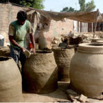 A potter shapes a traditional clay oven at his workplace in outskirts area of the provincial capital