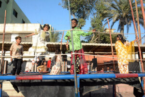 Children enjoy riding swing on a vendor’s setup on the third day of Eid al-Fitr in Chanesar Goth