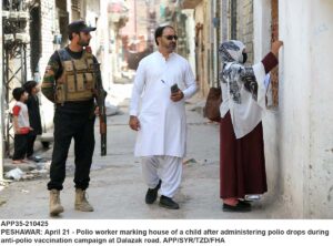 Polio worker marking finger of a child after administering polio drops during anti-polio vaccination campaign at Dalazak road.