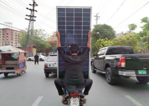 Motorcyclists carry solar panels on Davis Road under Punjab Chief Minister’s solar scheme, aimed at reducing electricity bills for low-consumption households