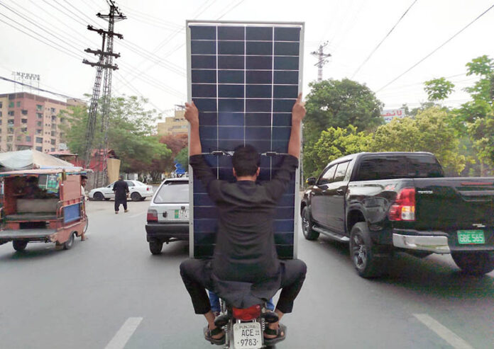 Motorcyclists carry solar panels on Davis Road under Punjab Chief Minister’s solar scheme, aimed at reducing electricity bills for low-consumption households