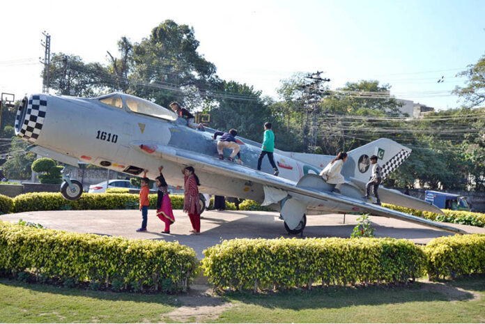 Children enjoy their holidays and taking pictures with a Pakistan Air Force plane displayed as a monument at China Chowk