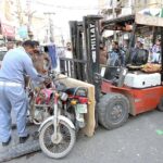 A traffic police officer removes wrong parked motorcycles to clear the road to ensure smooth traffic flow at Bara Bazaar in the city