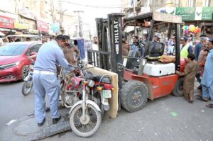 A traffic police officer removes wrong parked motorcycles to clear the road to ensure smooth traffic flow at Bara Bazaar in the city