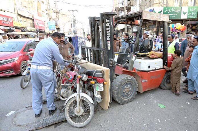 A traffic police officer removes wrong parked motorcycles to clear the road to ensure smooth traffic flow at Bara Bazaar in the city