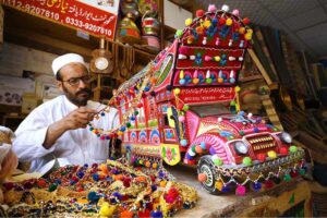 A craftsman is giving final touches to a handmade traditional colorful truck at his workplace near Dabgari area.