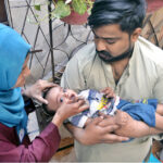 A lady health worker administers polio drops to a child during the anti-polio campaign